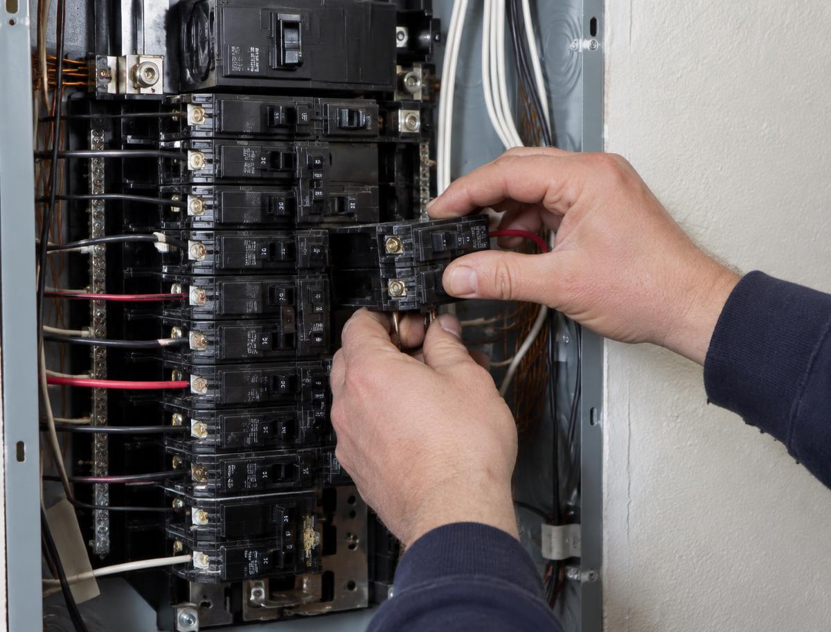 Electrician wiring a new breaker into a home electrical panel to feed a Level 2 EV charger circuit in Omaha