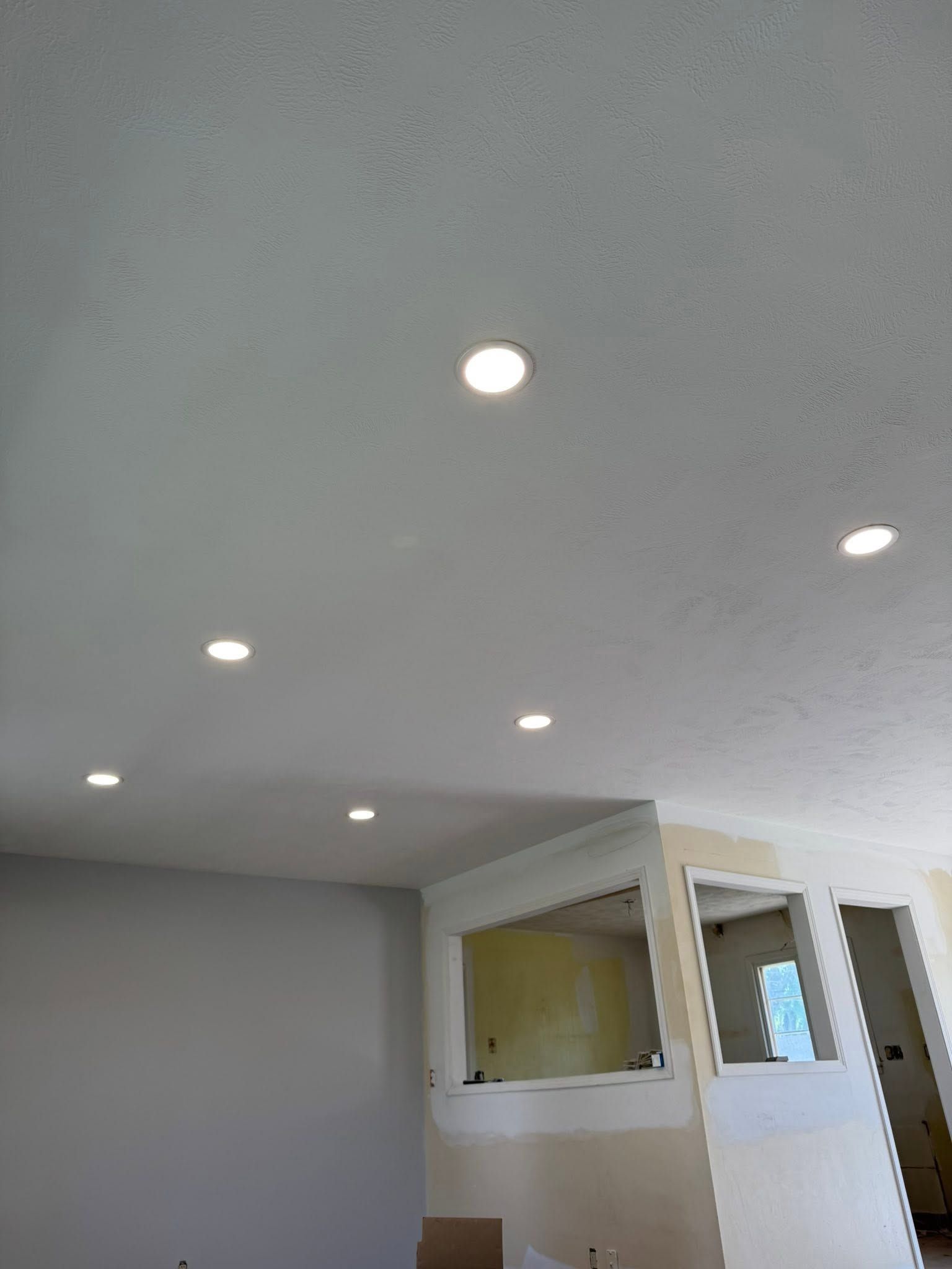 White room ceiling with recessed lights and a partial wall opening above a door.