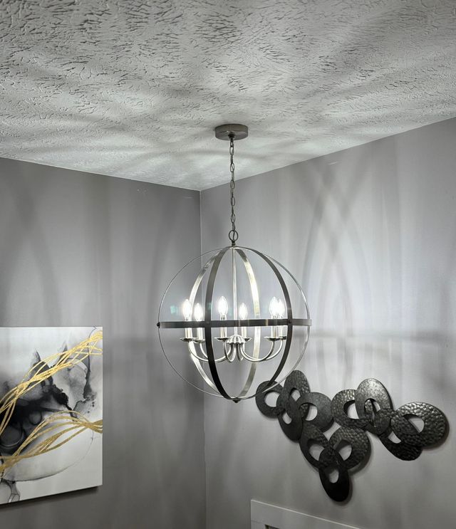 Modern room corner with a silver spherical pendant light, textured ceiling, gray walls, and abstract wall art.